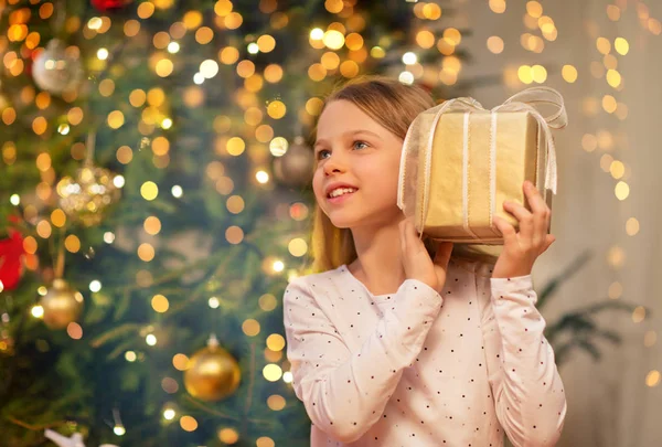 Leende flicka med julklapp hemma — Stockfoto