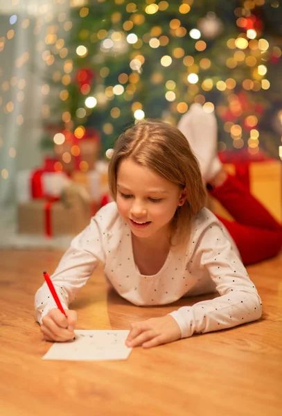 Sorridente ragazza scrittura lista dei desideri di Natale a casa — Foto Stock