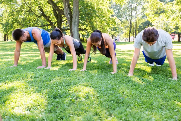 Personas haciendo flexiones o tablones en el parque de verano —  Fotos de Stock