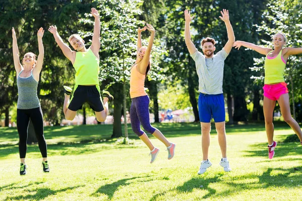 Csoport boldog barátok ugrás magas a parkban — Stock Fotó