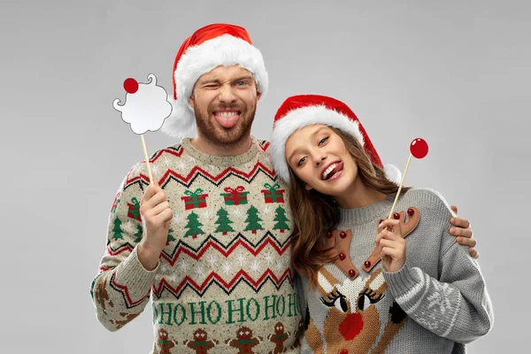 Pareja con accesorios de fiesta de Navidad en suéteres feos —  Fotos de Stock