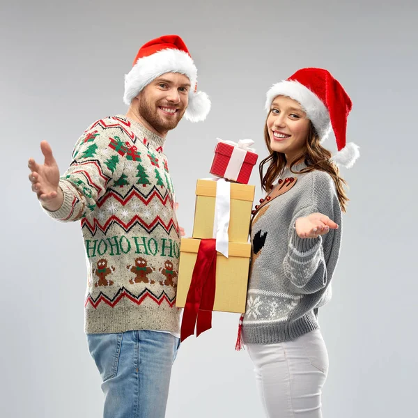 Feliz pareja en suéteres de Navidad con regalos —  Fotos de Stock