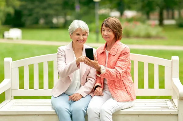 Happy senior women with smartphone at summer park — Stock Photo, Image