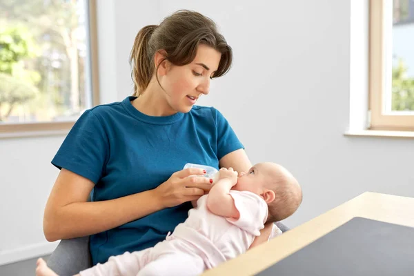 Mother feeding baby daughter with milk formula — Stock Photo, Image