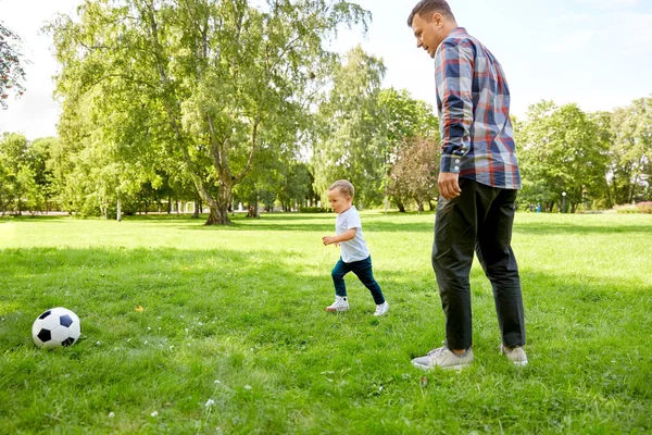 Far med liten son spelar fotboll i parken — Stockfoto