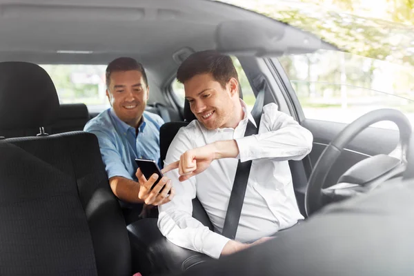 Passageiro masculino mostrando smartphone para motorista de carro — Fotografia de Stock