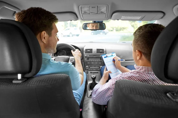 car driving instructor with clipboard and driver