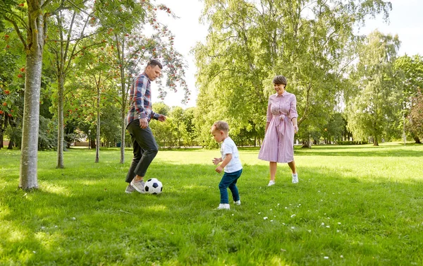 Счастливая семья играет в футбол в летнем парке — стоковое фото