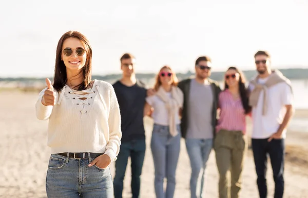 Kvinna med vänner på stranden visar tummen upp — Stockfoto