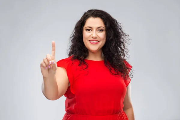 Gelukkig vrouw in rood jurk tonen een vinger — Stockfoto