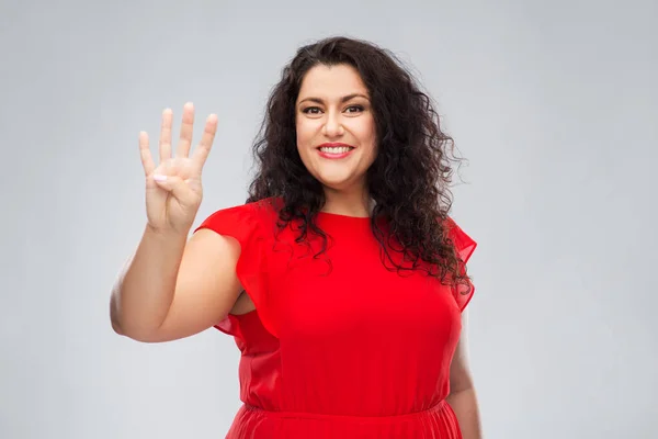 Kırmızı elbiseli mutlu kadın dört parmağını gösteriyor. — Stok fotoğraf
