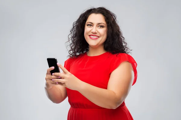 Femme heureuse en robe rouge en utilisant smartphone — Photo