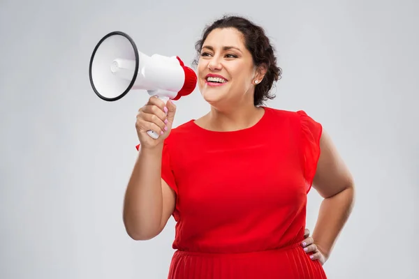 Šťastná žena v červených šatech mluví k megafonu — Stock fotografie