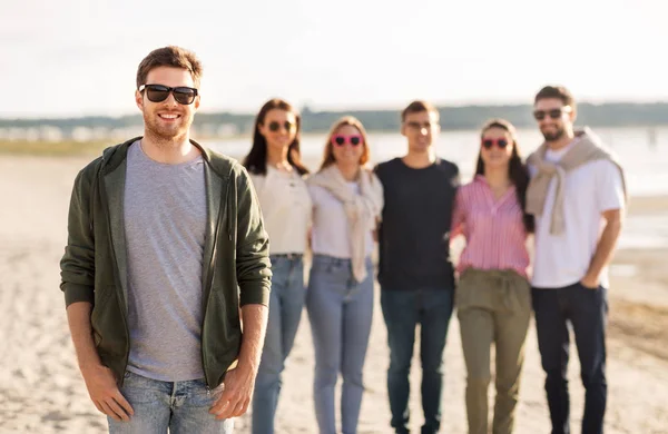 Hombre feliz con amigos en la playa en verano — Foto de Stock