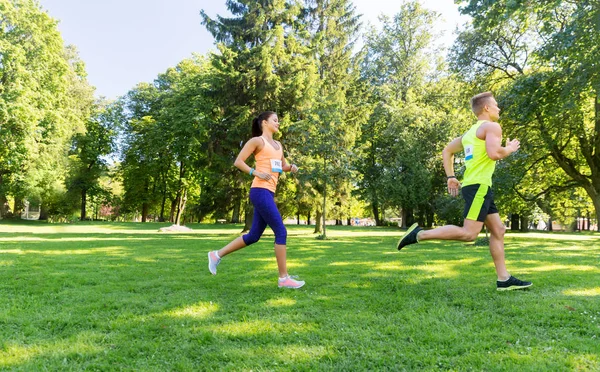 Ευτυχισμένο ζευγάρι αθλητών που τρέχουν με αριθμούς σήματος ευφυΐας — Φωτογραφία Αρχείου