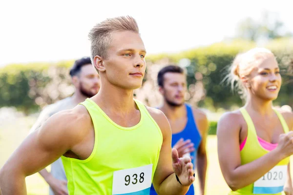 Happy young sportsmen racing wit badge numbers — Stock Photo, Image