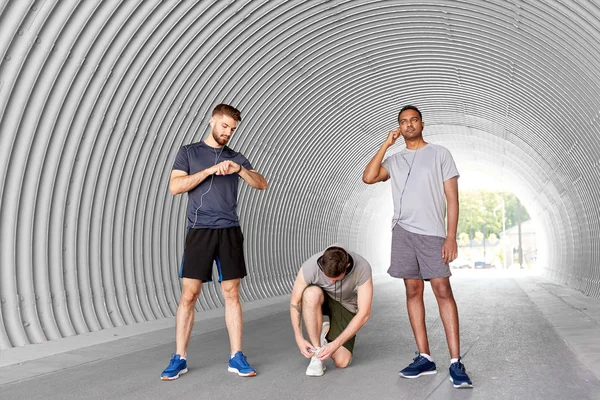 Male friends with earphones training outdoors — Stock Photo, Image