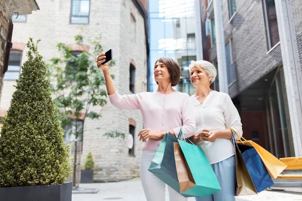Stare kobiety z torby na zakupy robienia selfie w mieście — Zdjęcie stockowe