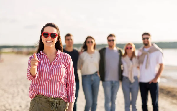 Kvinna med vänner på stranden visar tummen upp — Stockfoto