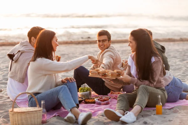 Amis heureux manger des sandwichs au pique-nique sur la plage — Photo