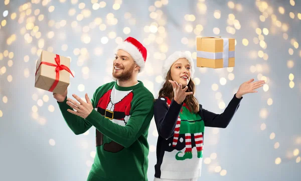 Casal feliz em camisolas feias com presente de Natal — Fotografia de Stock