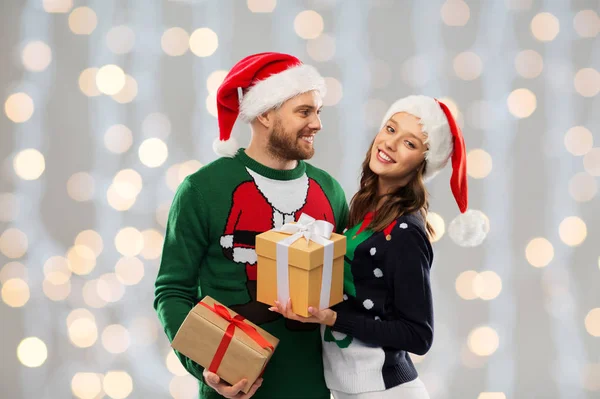 Happy couple in christmas sweaters with gifts — Stock Photo, Image