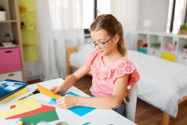 Dziewczyna z kolorowym papierem siedząc przy stole w domu — Zdjęcie stockowe