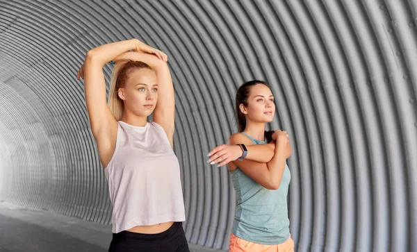 Kobiety z trackerów fitness rozciągające się na zewnątrz — Zdjęcie stockowe