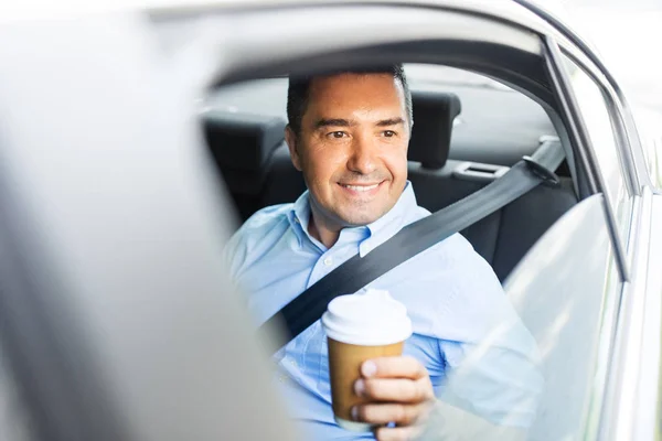 Biznesmen z kawą na wynos na tylnym siedzeniu samochodu — Zdjęcie stockowe