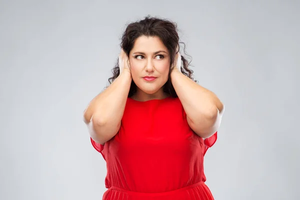 Kvinna i röd klänning stänga öronen med händerna — Stockfoto