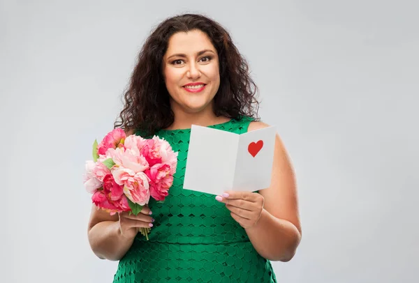 Mulher feliz com cacho de flores e cartão de saudação — Fotografia de Stock