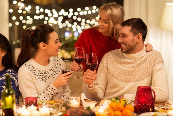 Glada vänner dricker rött vin på julfesten — Stockfoto