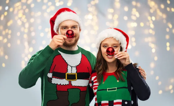 Happy couple in christmas sweaters and santa hats — Stock Photo, Image