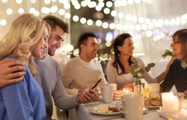 Glückliches Paar mit Smartphone bei Familien-Teeparty — Stockfoto