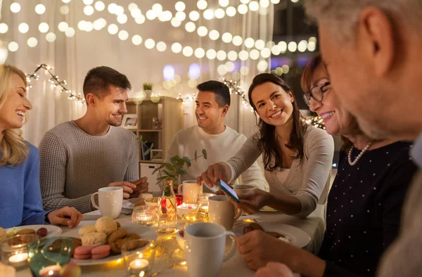 Família feliz com smartphone na festa de chá em casa — Fotografia de Stock