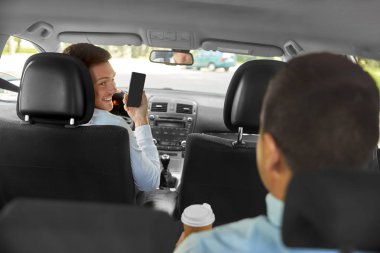 car driver showing smartphone to male passenger clipart