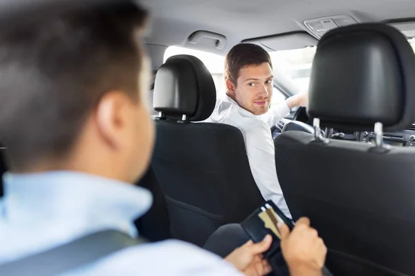 Manlig bilförare tittar på passagerare med plånbok — Stockfoto