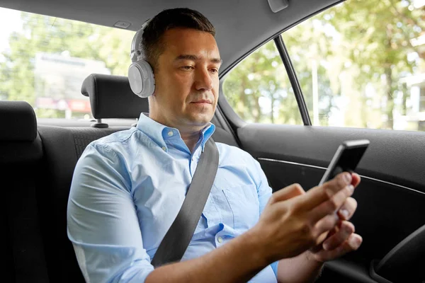 Passagerare med hörlurar med smartphone i bilen — Stockfoto