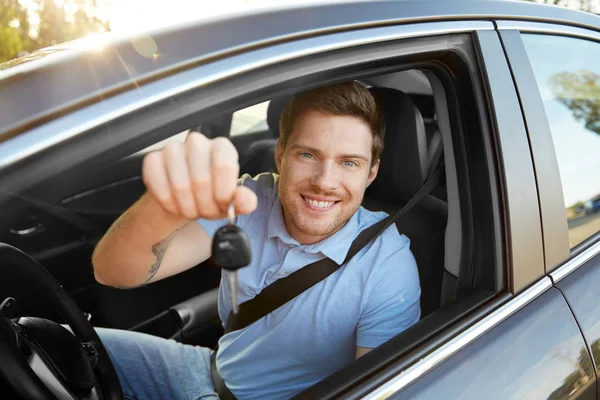 Sorridente homem ou motorista com chave sentado no carro — Fotografia de Stock