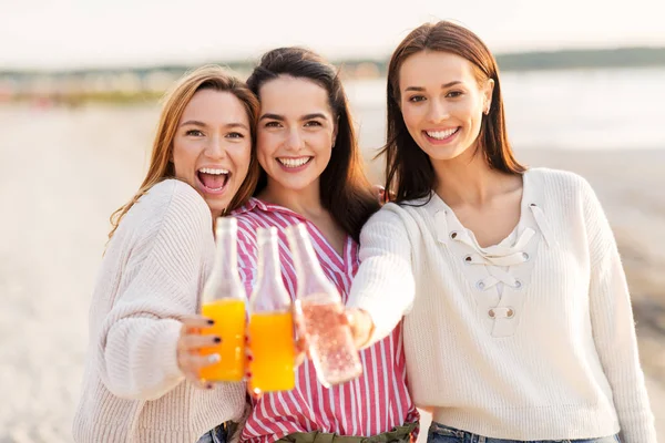 Mujeres jóvenes brindando bebidas no alcohólicas en la playa — Foto de Stock