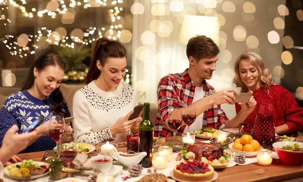 Друзья со смартфонами на рождественский ужин — стоковое фото