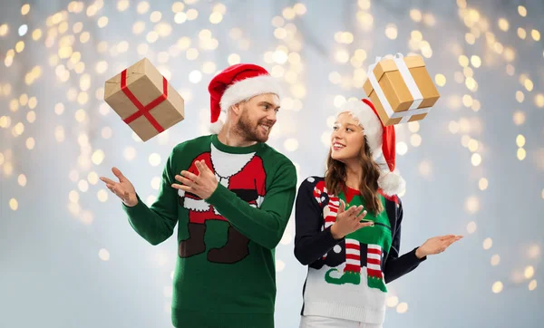 Happy couple in ugly sweaters with christmas gifts — Stock Photo, Image