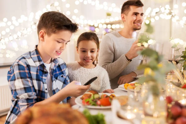 Barn med smartphone på familjemiddag fest — Stockfoto