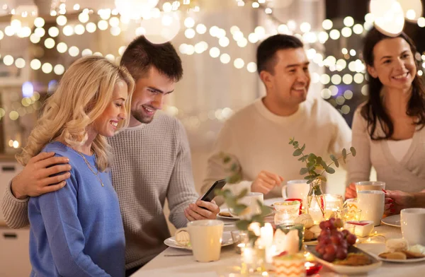 Gelukkige vrienden met smartphone op thee feestje thuis — Stockfoto