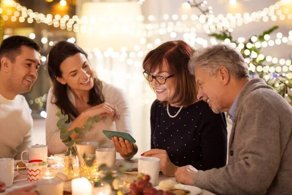 Família feliz com smartphone na festa de chá em casa — Fotografia de Stock