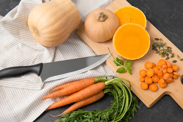 Calabaza cortada, zanahorias y cuchillo de cocina en la mesa —  Fotos de Stock