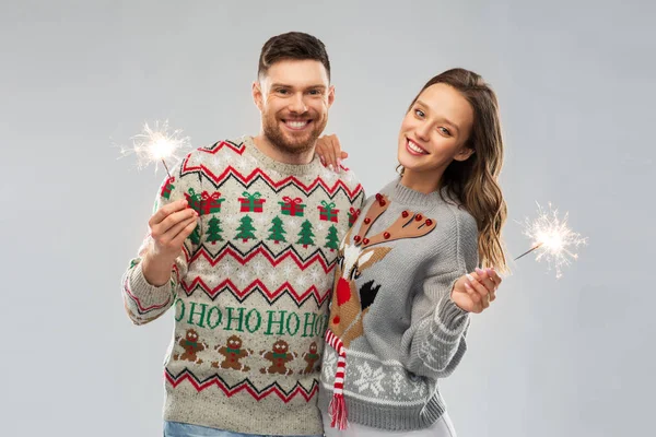 Feliz pareja en suéteres de Navidad con chispas —  Fotos de Stock