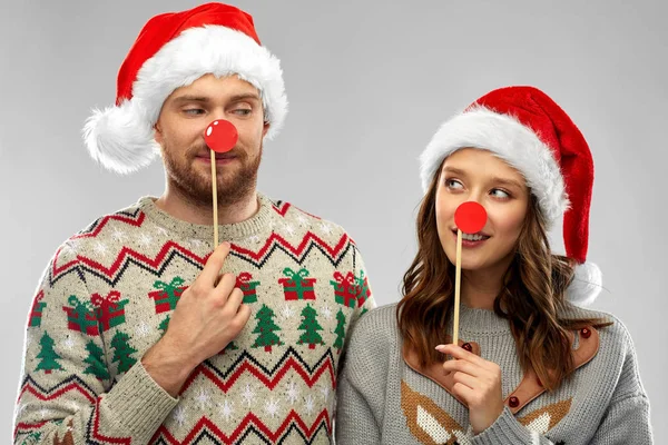 Par med julfest rekvisita i fula tröjor — Stockfoto