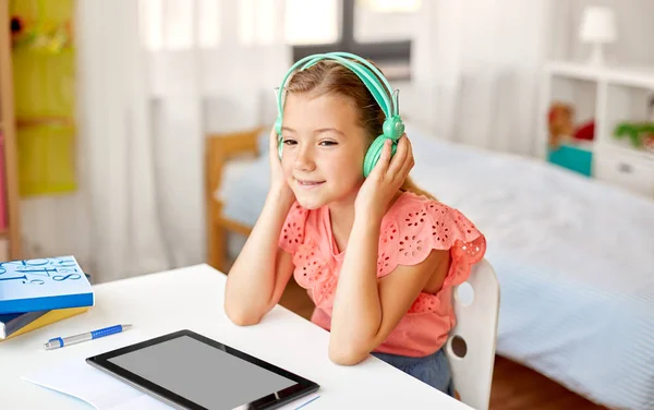 Meisje in hoofdtelefoon met tablet computer thuis — Stockfoto
