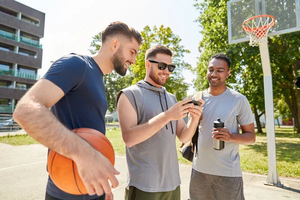 Мужчины со смартфоном на баскетбольной площадке — стоковое фото